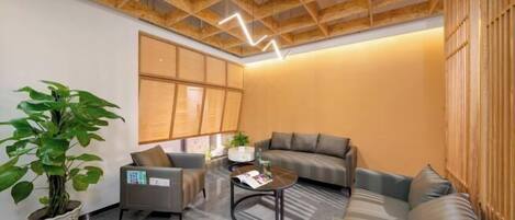 Una sala de estar moderna con techo de madera, sofás grises, una mesa de centro y una planta grande en maceta.
