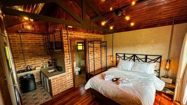 A cozy room with a bed, a small kitchenette, and a bathroom.