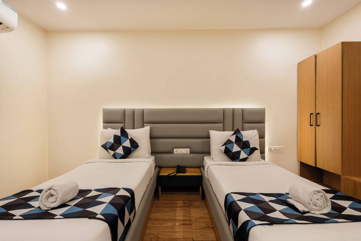 Ein Hotelzimmer mit zwei Betten, einem Holzschrank und einem Nachttisch mit Telefon.