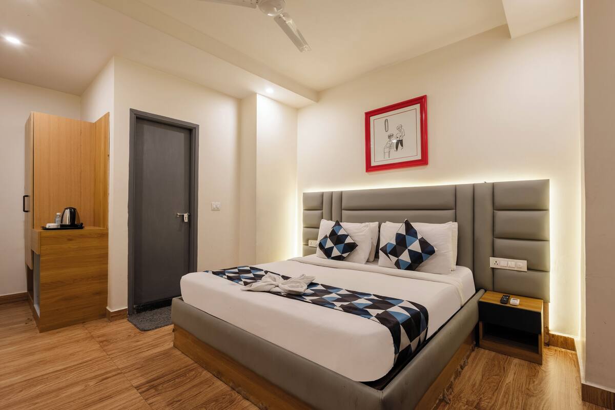 Ein modernes Hotelzimmer mit einem großen Bett, einem Nachttisch, einem Kleiderschrank und einem gerahmten Bild an der Wand.
