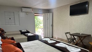 Una habitación de hotel con dos camas, televisión, una mesita y una silla.