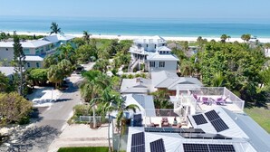 Um imóvel costeiro com várias construções, vista para a praia e painéis solares no telhado.