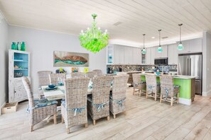 Een moderne keuken met witte kasten, een groen eiland en een roestvrijstalen koelkast.