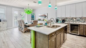Cozinha moderna com uma ilha grande, luminárias pendentes e área de jantar com cadeiras de vime.
