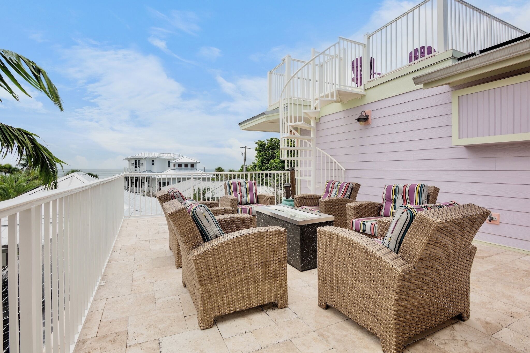 A balcony with wicker furniture and a view of the ocean.