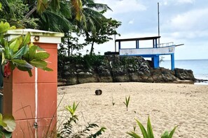 Une plage dotée d’une tour de surveillance pour les sauveteurs, d’un rivage rocheux et d’une végétation tropicale.