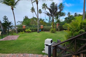 A well-maintained garden with a lawn, palm trees, and a brick pathway leading to a gated entrance. - Welcome to Costal Paradise! (Rincon)