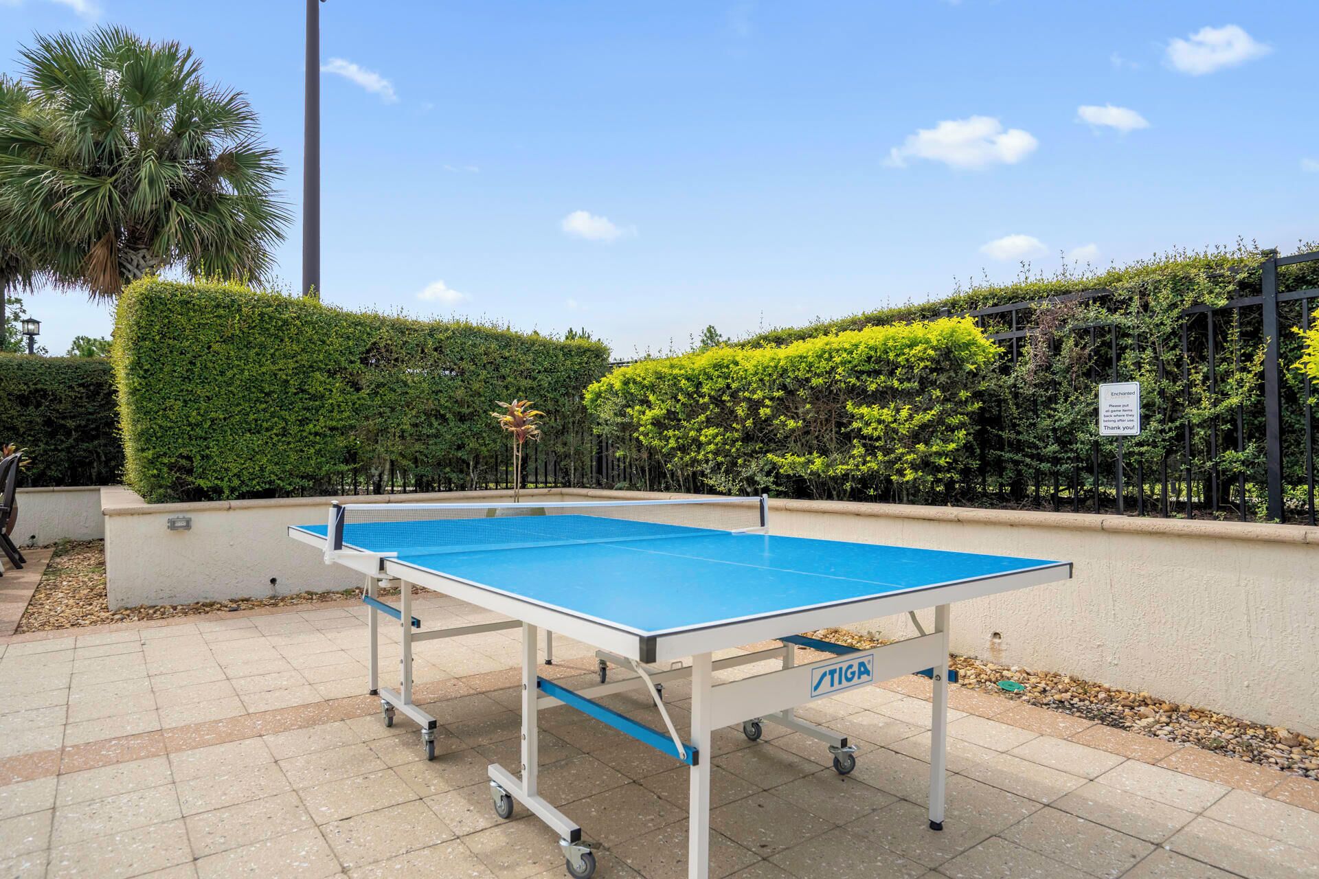 A portable ping pong table with wheels, labeled 'TIGA', set up outdoors on a tiled surface.