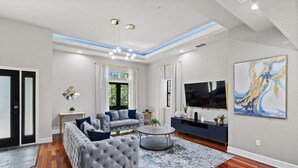Un salon moderne avec un canapé gris, une table basse ronde et un téléviseur à écran plat.