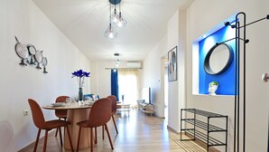 A dining area with a round table, four chairs, and a vase with blue flowers. - Royal Blue Central House by Checkin (Heraklion)