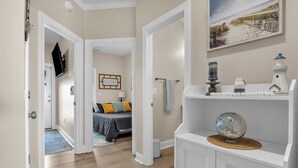 Un couloir comprenant un lit, un tableau et une étagère ornée d’objets décoratifs.