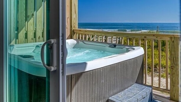 Un bain à remous sur une terrasse en bois, avec vue sur l’océan.