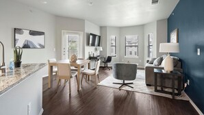 A modern living room with a grey sofa, a coffee table, and a TV mounted on the wall.