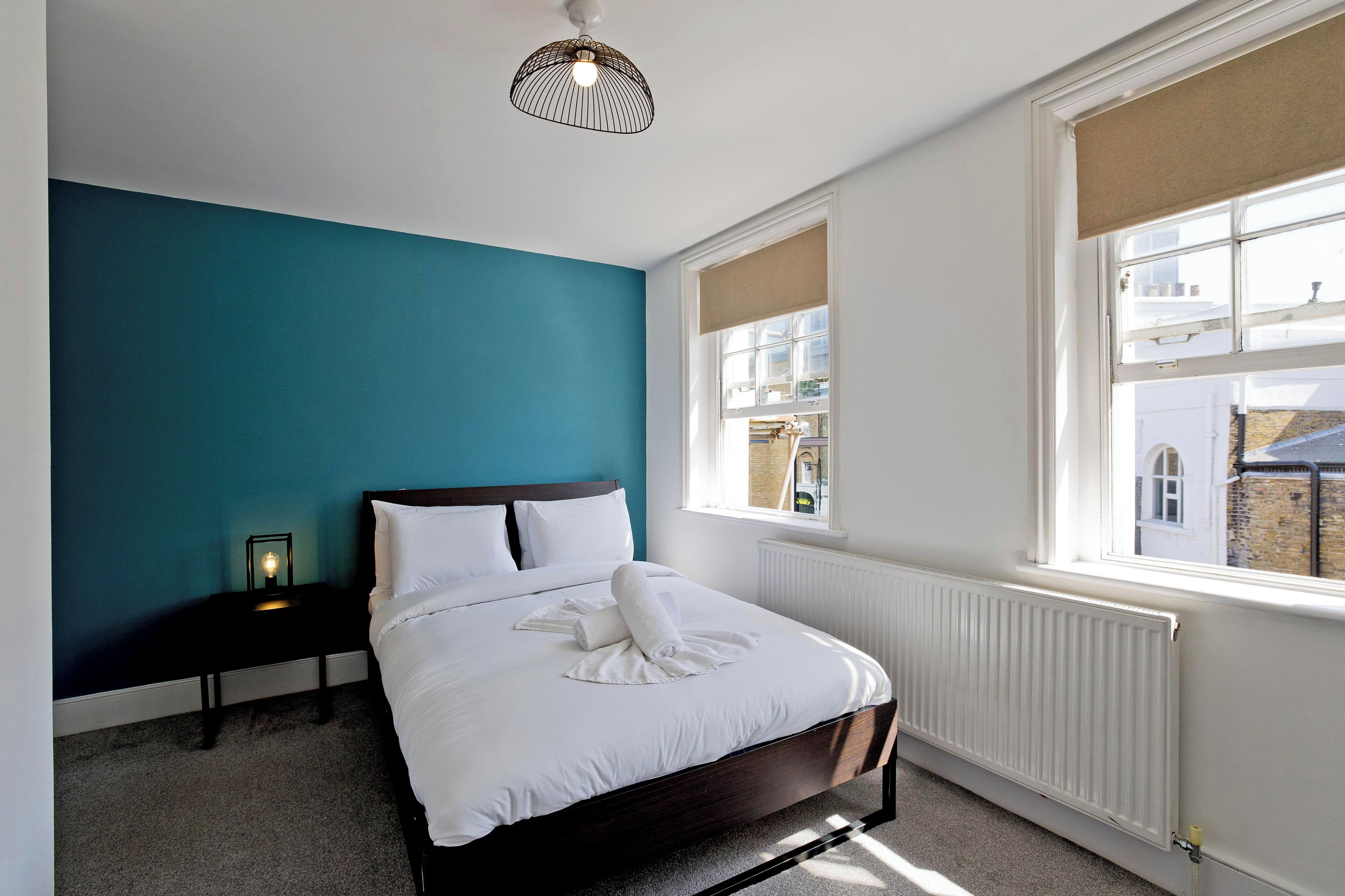 Een slaapkamer met een bed, een nachtkastje, een raam en een radiator.