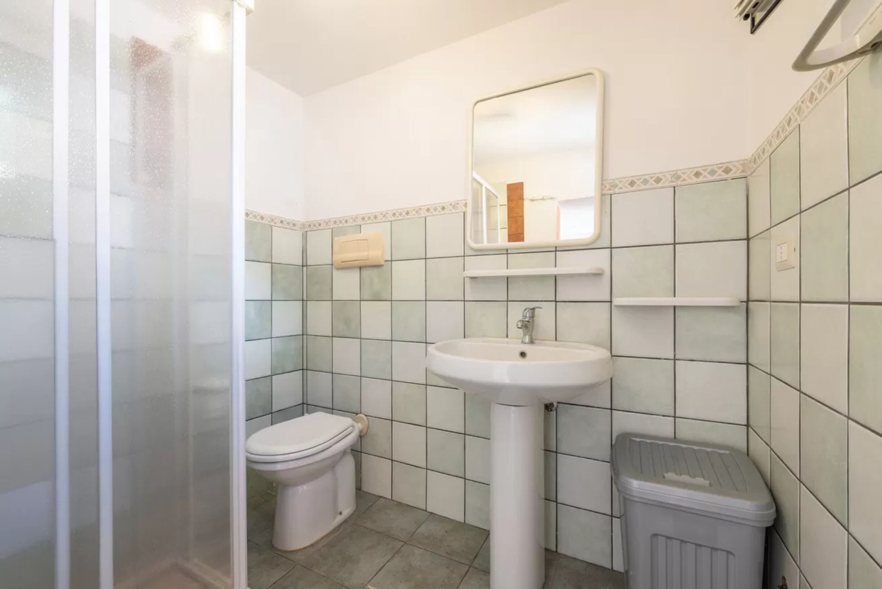 A bathroom with a toilet, sink, and mirror.