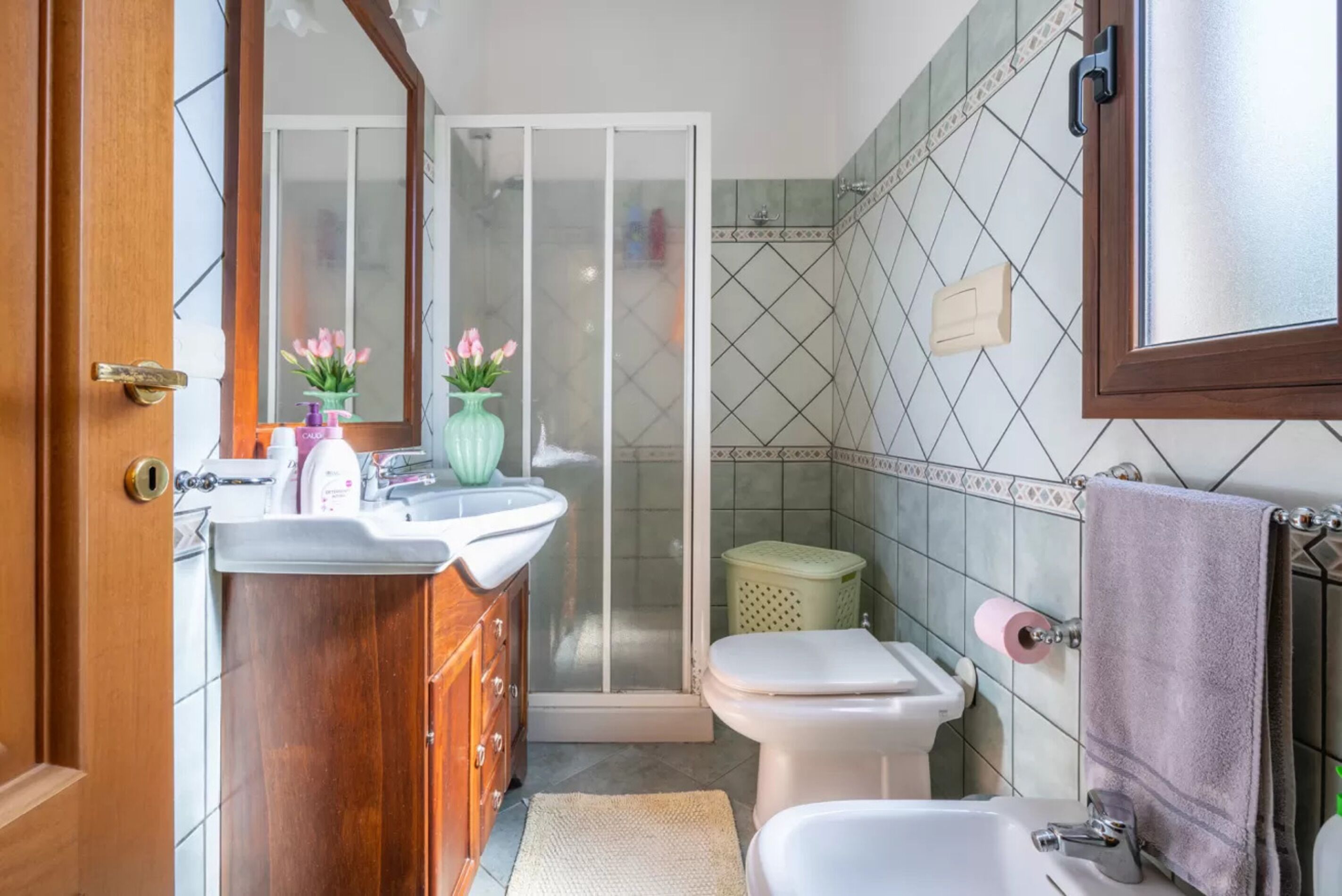 A bathroom with a wooden vanity, a shower, and a toilet.