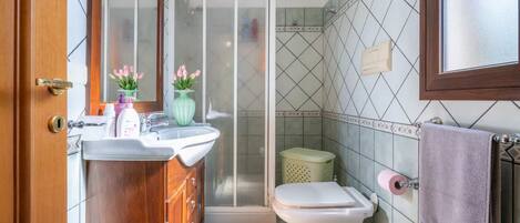A bathroom with a wooden vanity, a shower, and a toilet.