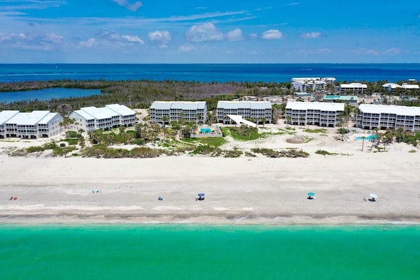 A beachfront hotel with multiple buildings, a sandy beach, and clear turquoise waters.