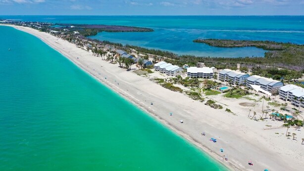A coastal hotel with multiple buildings, a sandy beach, and clear turquoise waters. - Direct Beachfront and View | Walk-Out to Sand | Pool + Pickleball + Tennis | (Captiva)