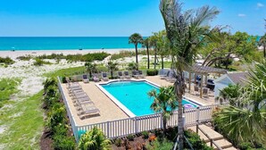 A pool area with lounge chairs, a pergola, and a view of the beach. - Direct Beachfront and View | Walk-Out to Sand | Pool + Pickleball + Tennis | (Captiva)