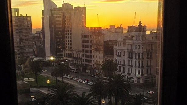 A cityscape at sunset with buildings and a clear sky.