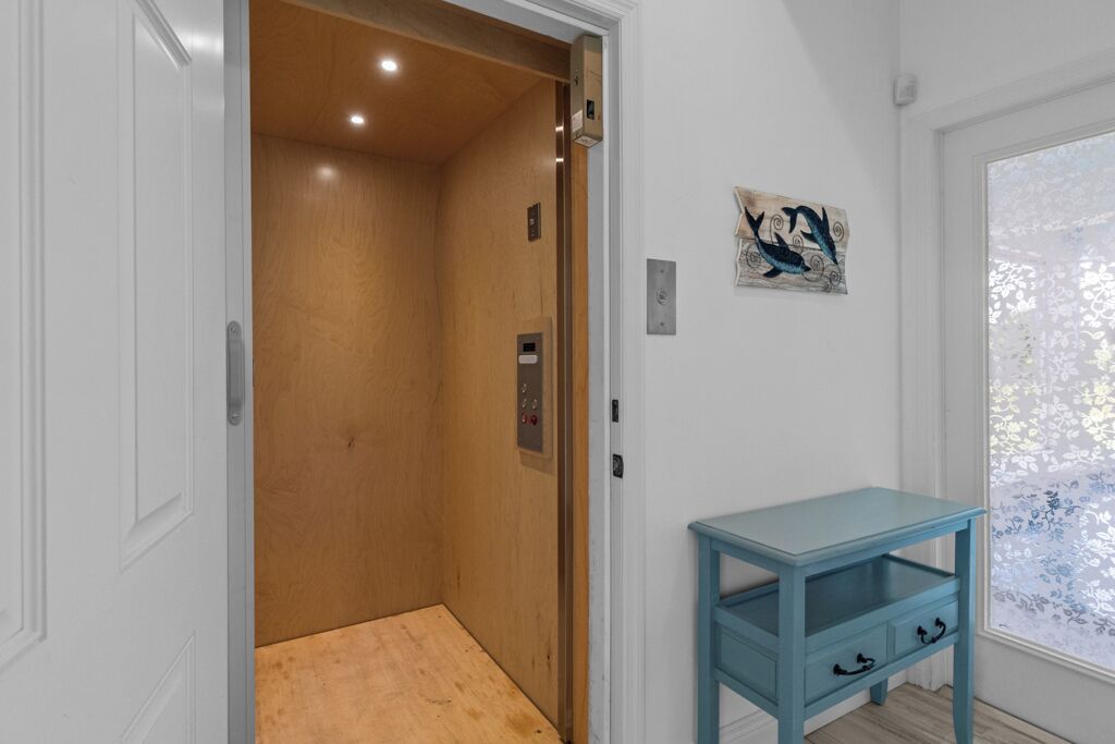 An elevator with wooden walls and a blue table beside it.