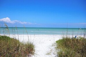 A beach with a sandy path leading to the water, surrounded by grass. - Discover Coastal Bliss at This Top-Floor Sanibel Escape (Sanibel)