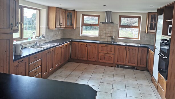 Una cocina con armarios de madera, encimera negra y salpicadero de azulejos.
