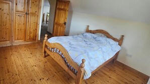 Un dormitorio con una cama de madera, un armario y una lámpara en el techo.