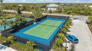 Vista aerea di un campo da tennis immerso nel verde con un'area parcheggio.