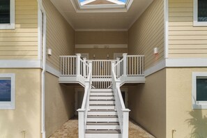 Una escalera conduce a un balcón con tragaluz, rodeado de paredes color beige y barandales blancos.