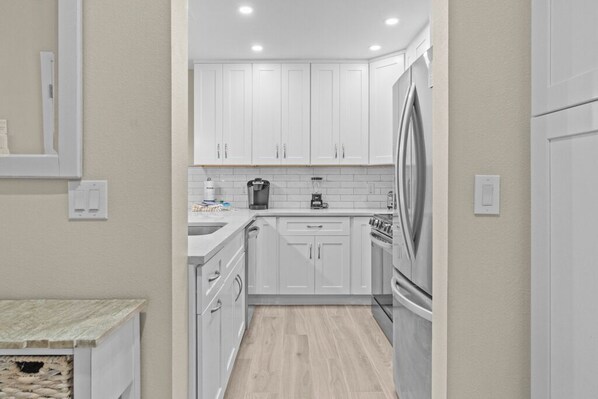 Una cocina moderna con armarios blancos, un refrigerador de acero inoxidable y un horno empotrado.