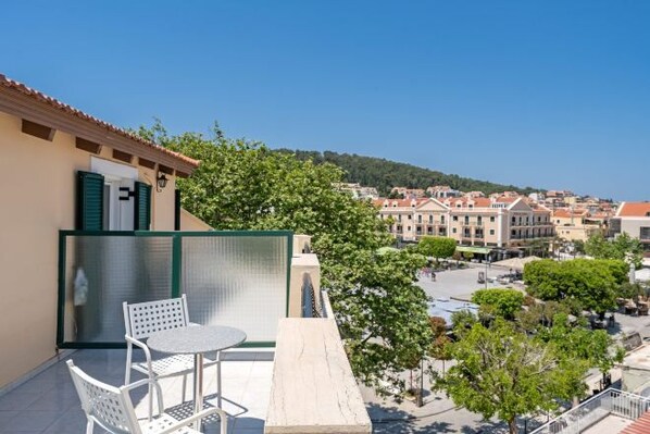 Un balcón con una mesa y sillas, con vista a un pueblo con edificios y árboles.