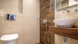 A bathroom with a toilet, a glass shower enclosure, and a sink with a wooden countertop. - Mirabel CityCenter Hotel (Argostolion)