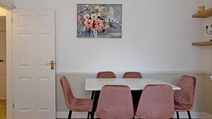 A dining area with a white table and four pink upholstered chairs.