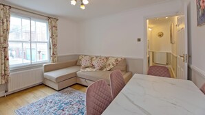 A cozy room with a white sofa, a dining table, and a patterned rug.