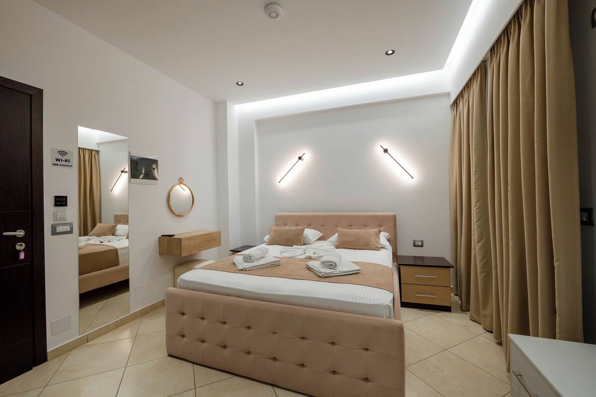 Un dormitorio moderno con una cama grande, mesitas de noche, un espejo y un armario.
