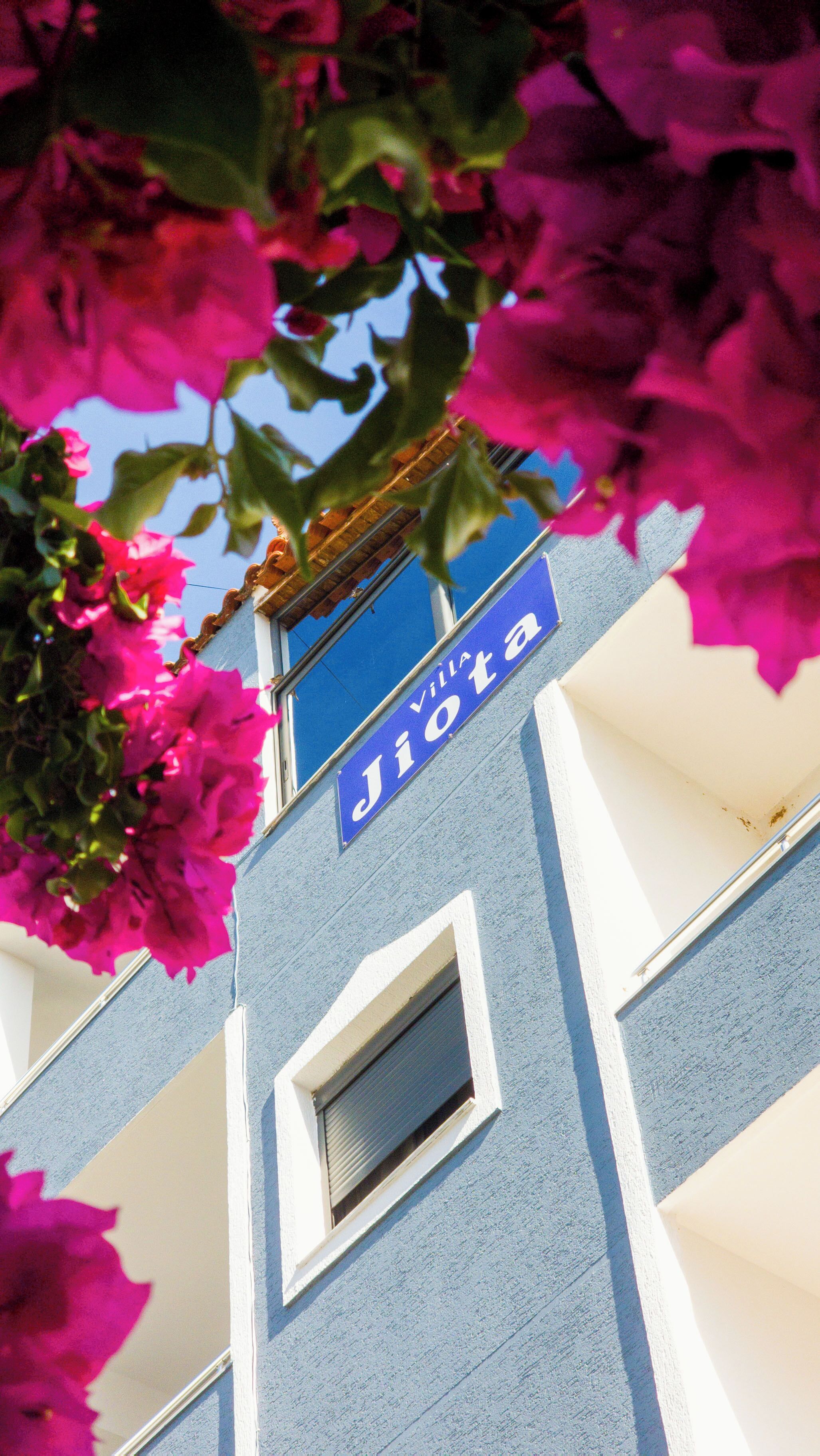 Un bâtiment avec une enseigne bleue sur laquelle on peut lire « Villa Jiota » et une fenêtre.