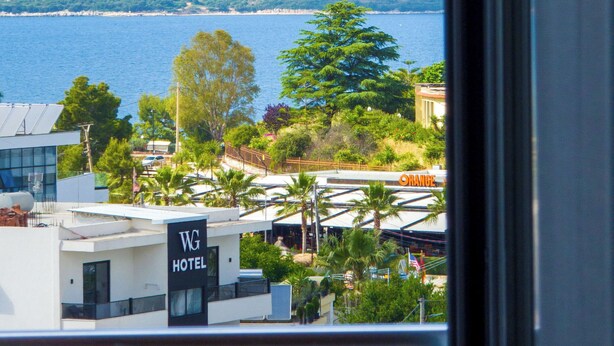 A view of a hotel with a sign labeled "WG HOTEL" and a restaurant named "WG HOTEL RESTAURANT" across the street. - Villa JIOTA (Ksamil)