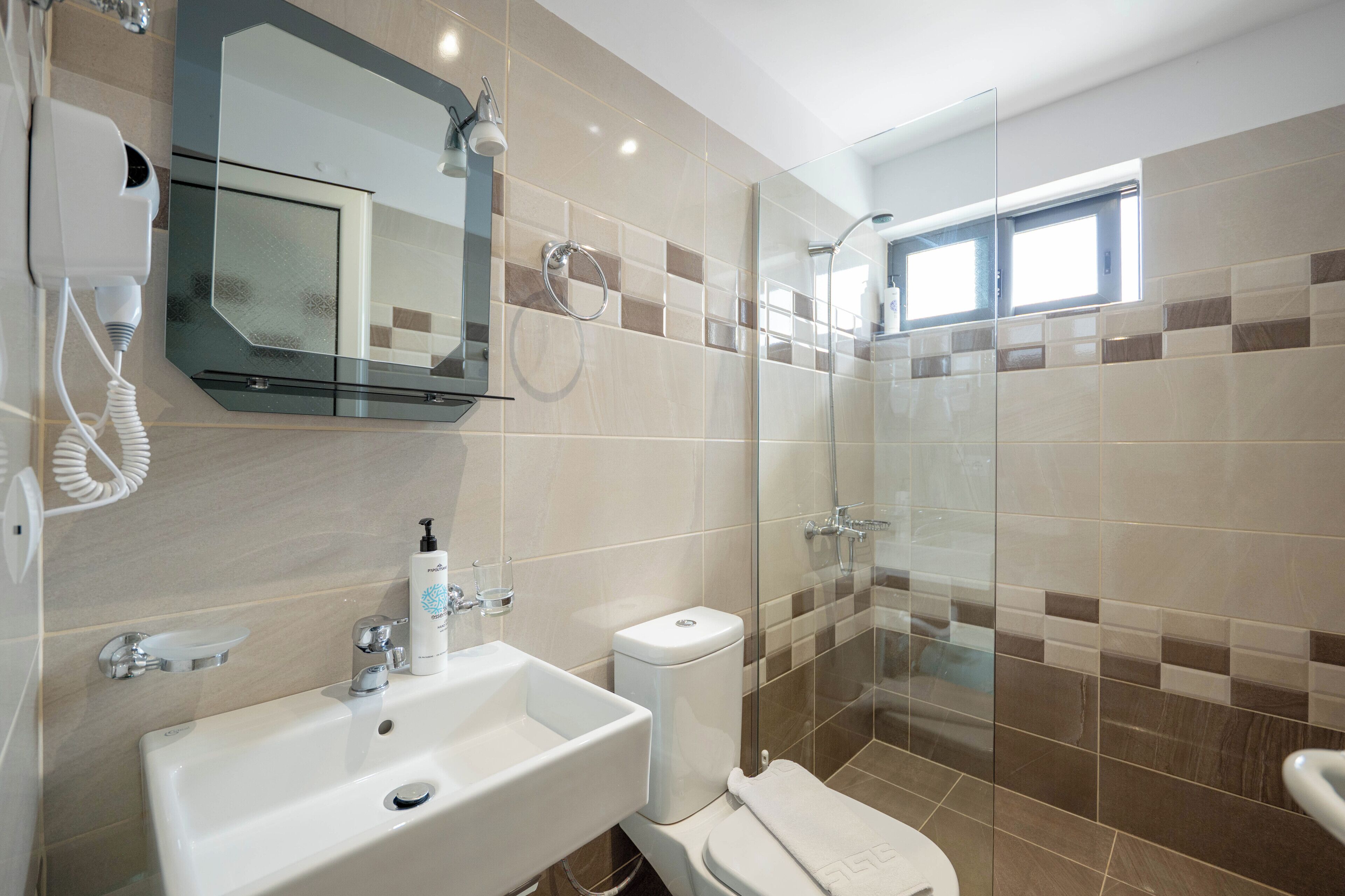A modern bathroom with a glass-enclosed shower, a white sink, and a toilet.