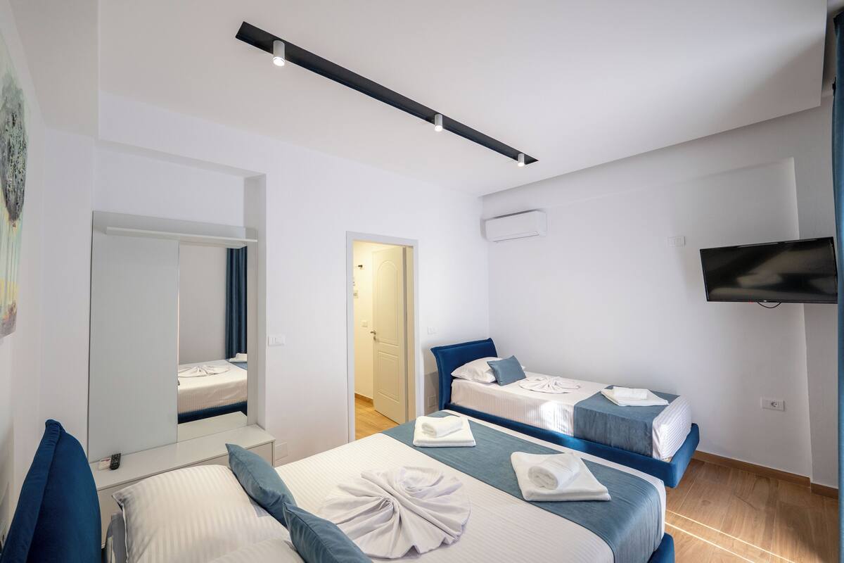 Una habitación de hotel moderna con dos camas, un televisor de pantalla plana y un espejo grande.