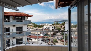 A balcony with a view of a coastal town, including buildings and mountains in the distance. - Villa JIOTA (Ksamil)
