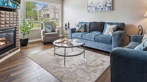 A living room with a fireplace, a blue sofa set, a round coffee table, and a lamp.