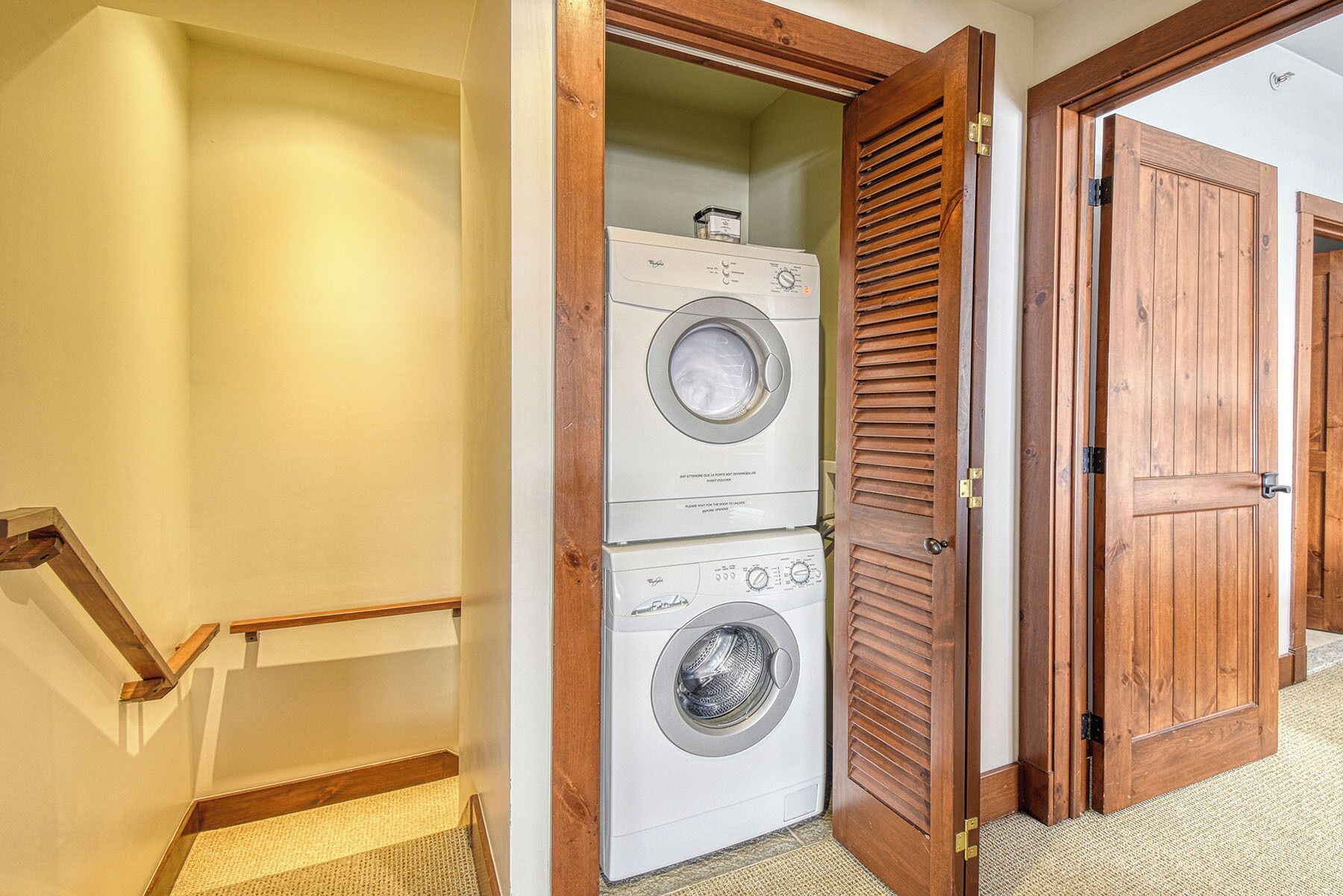 Un lavadero con dos lavadoras apiladas y una puerta de madera.