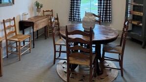 A dining area with a round wooden table, six chairs, a chandelier, and a window with checkered curtains. - Welcome to Victorian by the bay
Built in 1830 the oldest home in the village (Saint Martins)