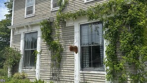 A two-story house with a Victorian-style sign, surrounded by lush greenery and flowering plants. - Welcome to Victorian by the bay
Built in 1830 the oldest home in the village (Saint Martins)