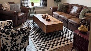 A living room with two brown leather sofas, a wooden coffee table, a patterned rug, and a checkered floor. - Welcome to Victorian by the bay
Built in 1830 the oldest home in the village (Saint Martins)