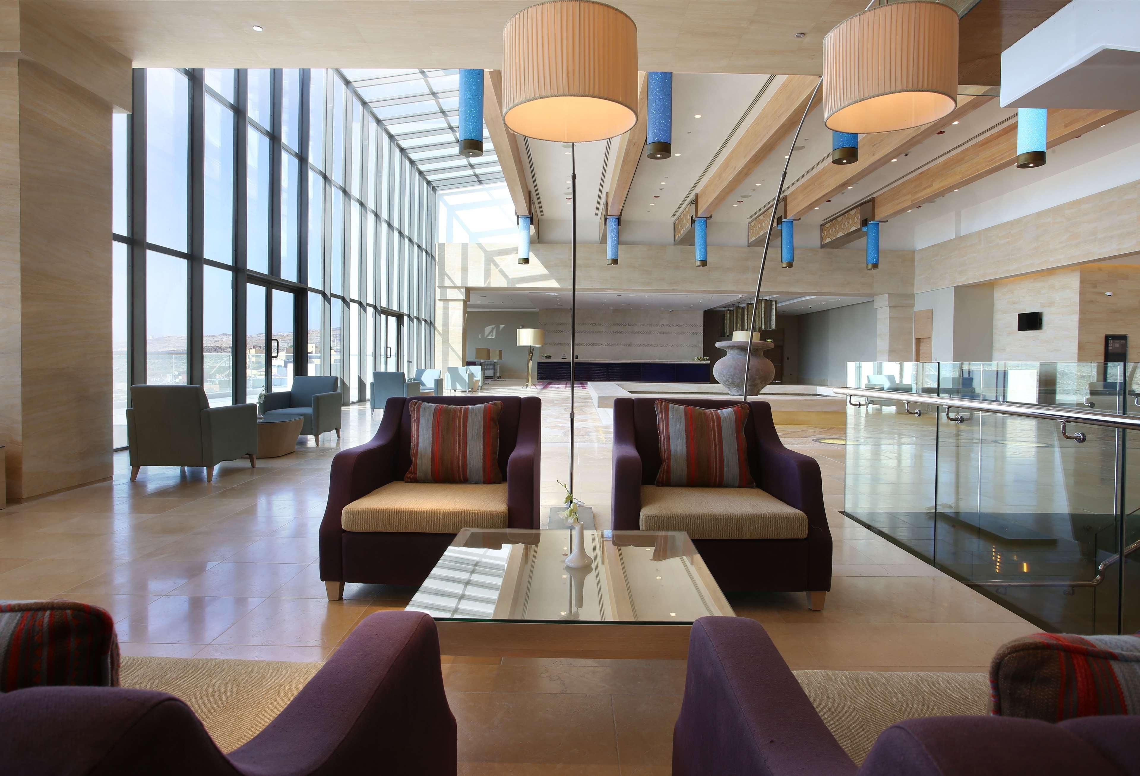 En rummelig lobby med højt til loftet, store vinduer og moderne møbler.