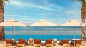 A beachside lounge with sun loungers and umbrellas, overlooking a clear blue sea. - Hilton Dead Sea Resort & Spa (Sweimeh)
