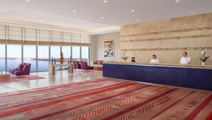 A spacious lobby with a reception desk, large windows, and a patterned carpet. - Hilton Dead Sea Resort & Spa (Sweimeh)